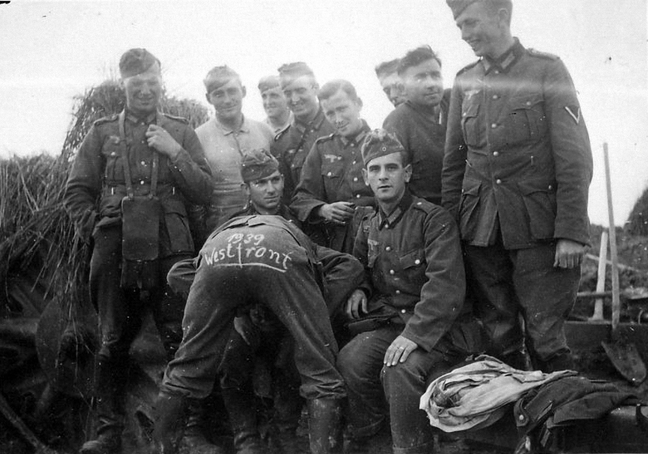 Немецкие солдаты развлекаются во время т. н. "Странной войны", периода Второй Мировой войны, во время которой боевые действия практически не велись. На заднице немца написано "1939 Западный фронт".
