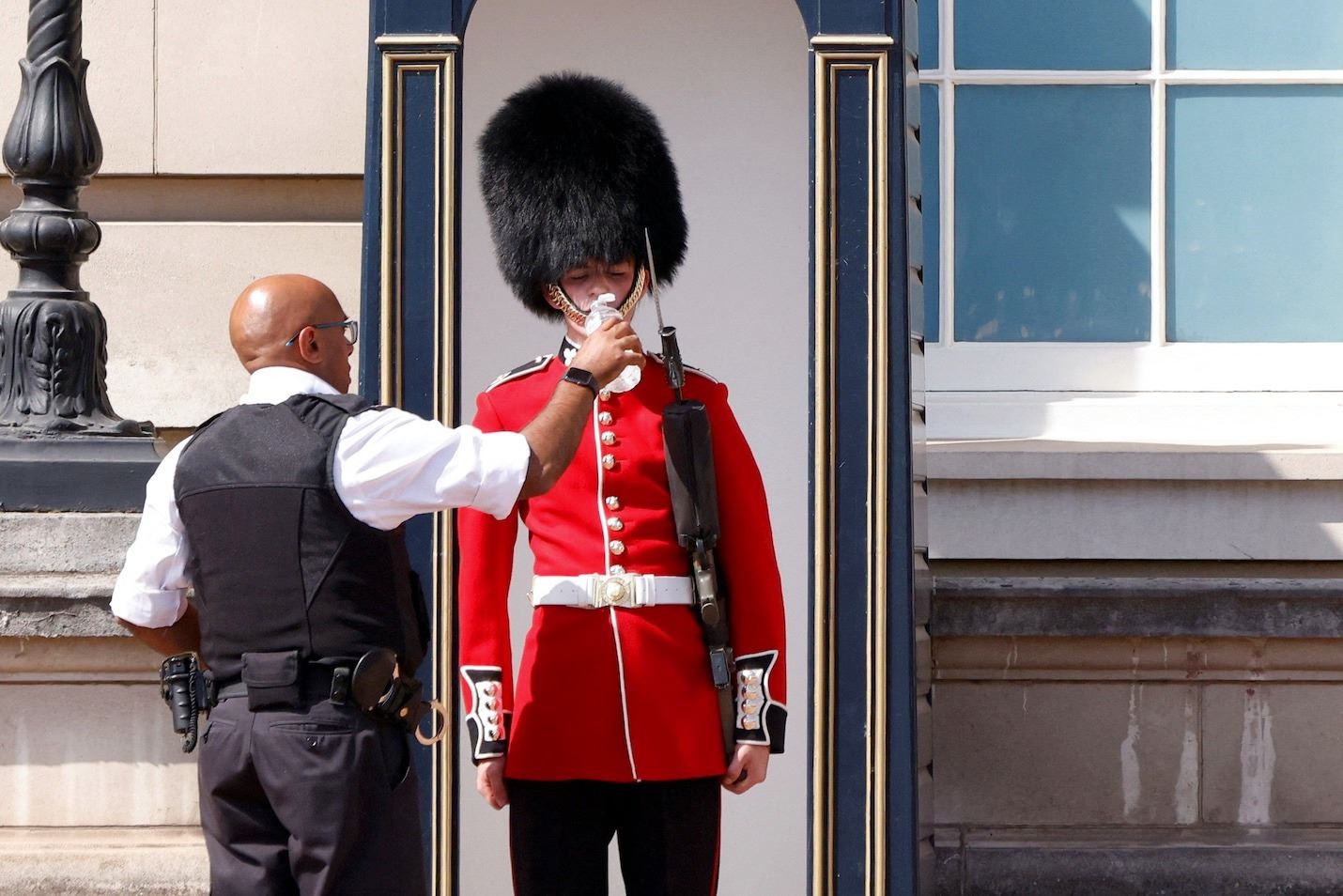 Лондонский полицейский дает попить караульному из Ирландского полка, Великобритания, 19 июля 2022 г.