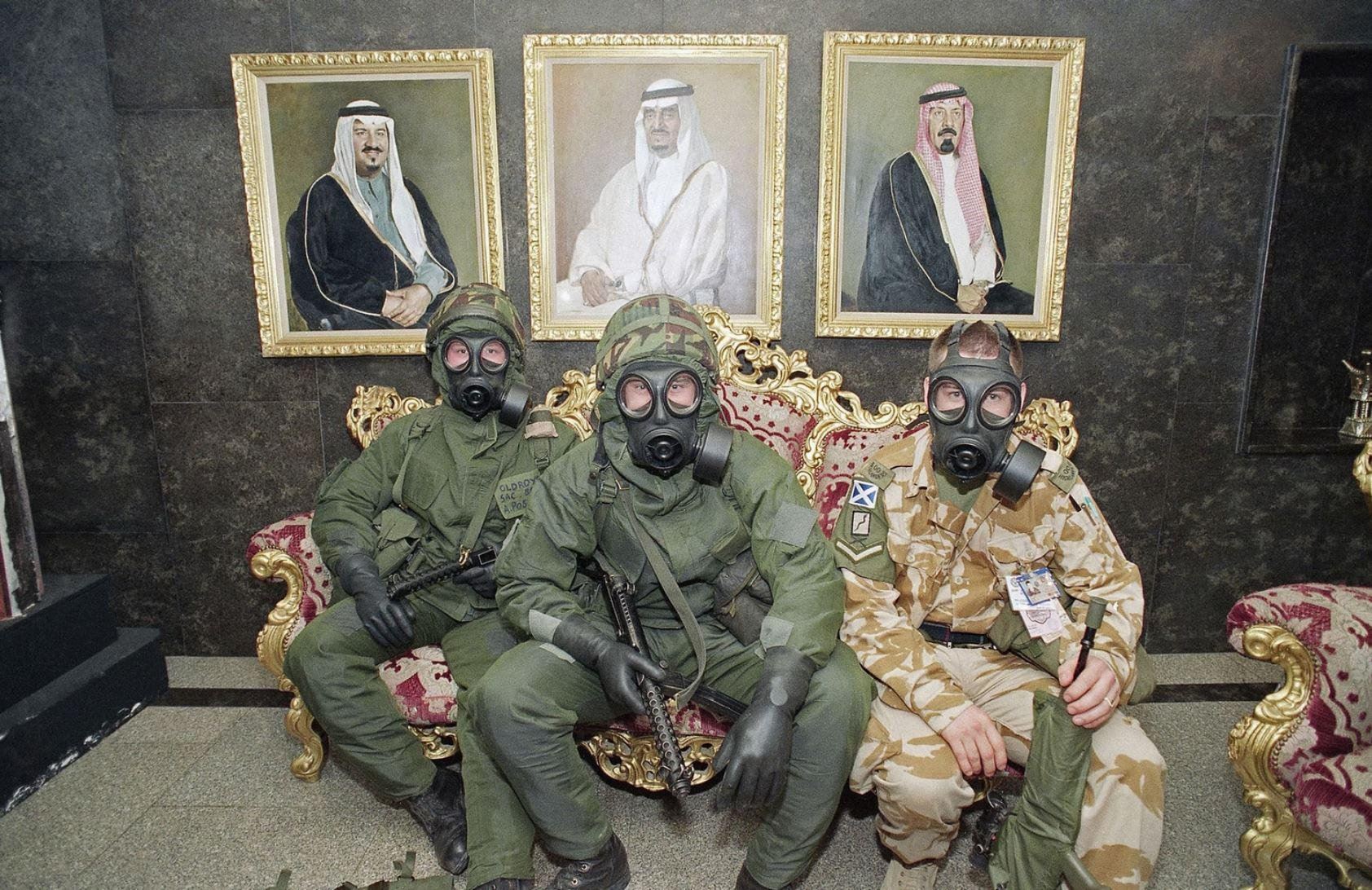 Трое британских солдат в полном боевом и противогазовом снаряжении ждут сигнала "все чисто" в вестибюле отеля во время атаки Р-17, Саудовская Аравия, 1991 г.
