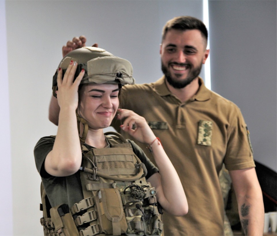 Украинский военный дает примерить военную амуницию девушке, Киев, 2019 г.