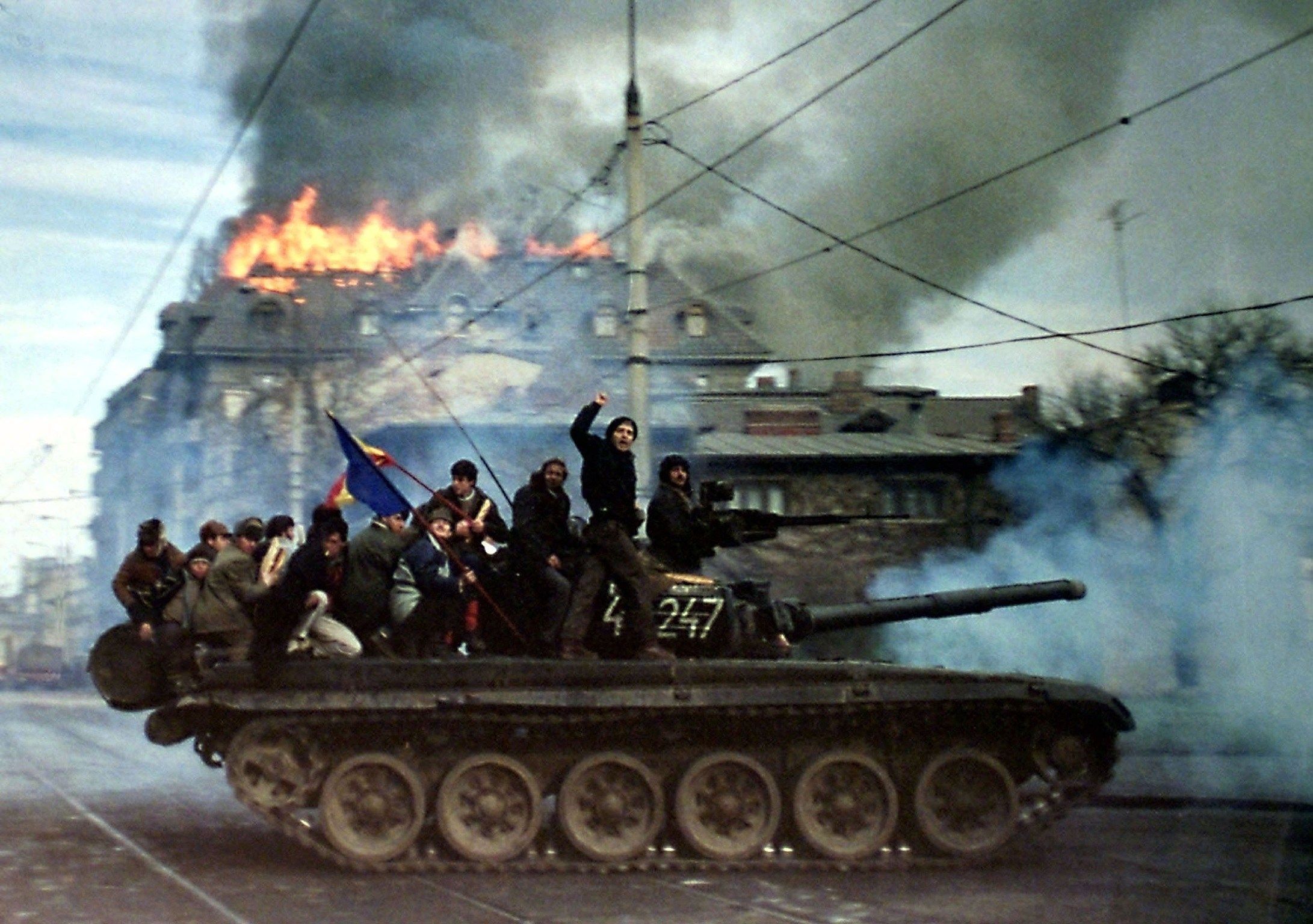 Демонстранты на танке Т-72 на фоне горящего здания во время Румынской революции, Бухарест, декабрь 1989 г.