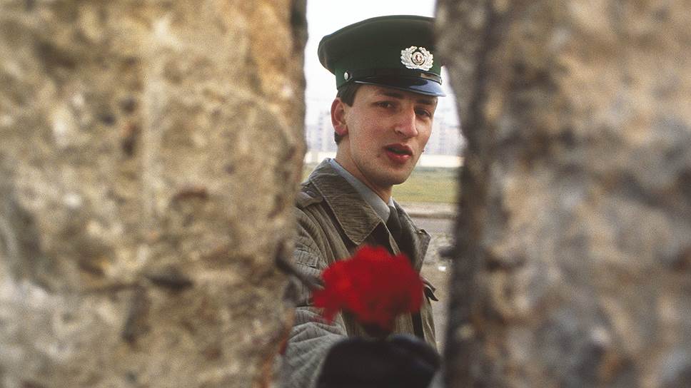 Солдат армии ГДР протягивает цветок через стену, 10 ноября 1989 г.