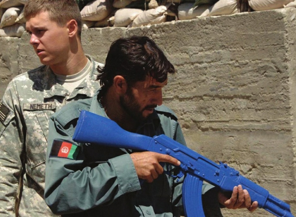 Американский солдат проводит учения с офицерами афганской национальной полиции, который держит синий пластиковый манекен AKM, используемый для тактической подготовки, 12 июня 2007 г.