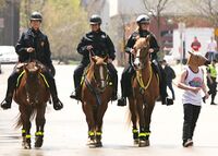 Студент в маске в виде лошадинной головы проходит мимо трех конных полицейских, патрулирующих город Западный Бенд, США, 2013 г..jpg