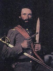 Capt. Houston Lowrie of the 6th North Carolina Infantry in full dress uniform holding his sword, Bowie knife, and revolve.jpg