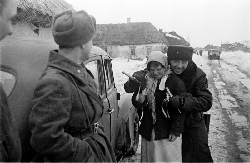 Советские офицеры беседуют с девушкой на сельской улице, один из них демонстрирует немецкий офицерский кортик, 1943 г.
