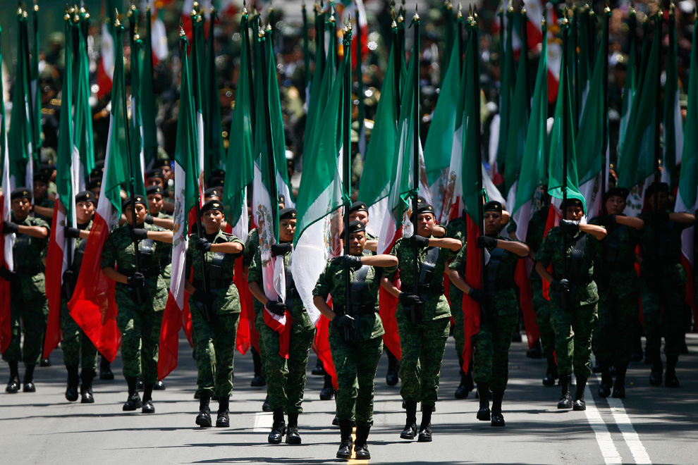 Девушки-военнослужащие с мексиканскими флагами маршируют на параде в честь Дня Независимости 16 сентября 2010 г.