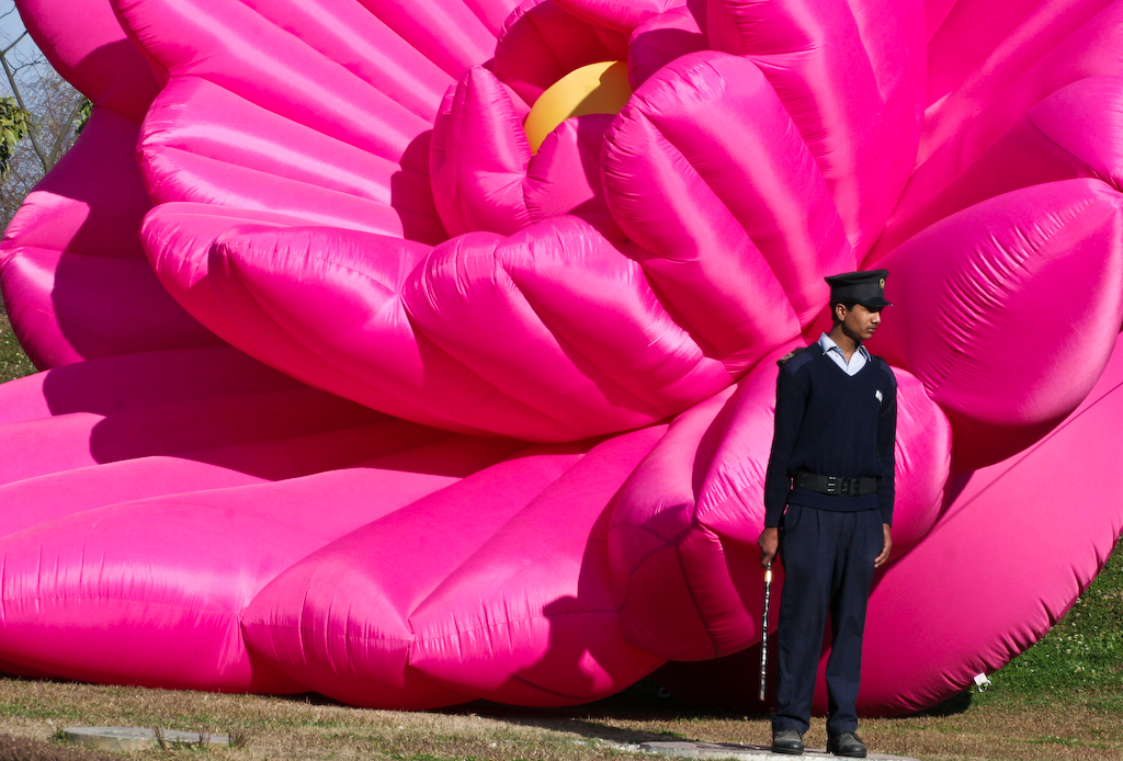 Непальский полицейский на фоне огромной надувной фигуры цветка, Катманду, 2008 г.