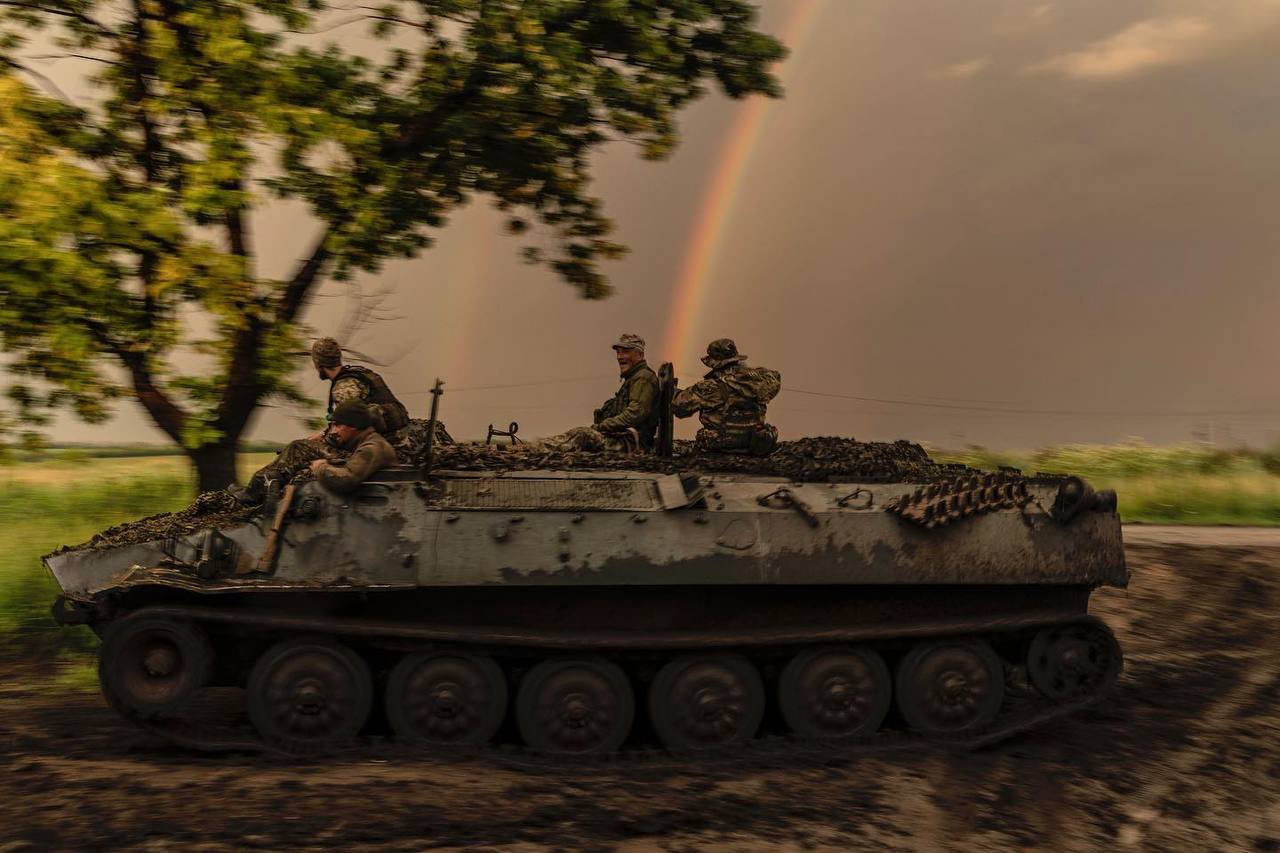 Украинские бойцы едут на МТ-ЛБ где-то около Бахмута, Донецкая область, 30 июня 2023 г. На фоне видна радуга.