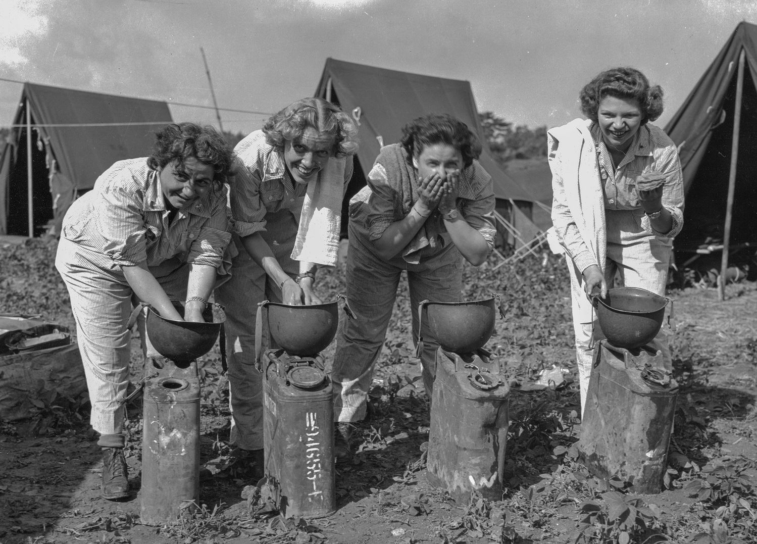 Первые американские медсестры, прибывшие в Окинаву, Япония, умываются с помощью каски M1, май 1945 г.