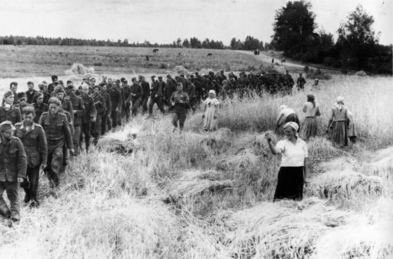 Женщина показывает кукиш немецким военнопленным, которых ведут советские конвоиры, Украина, 1944 г.