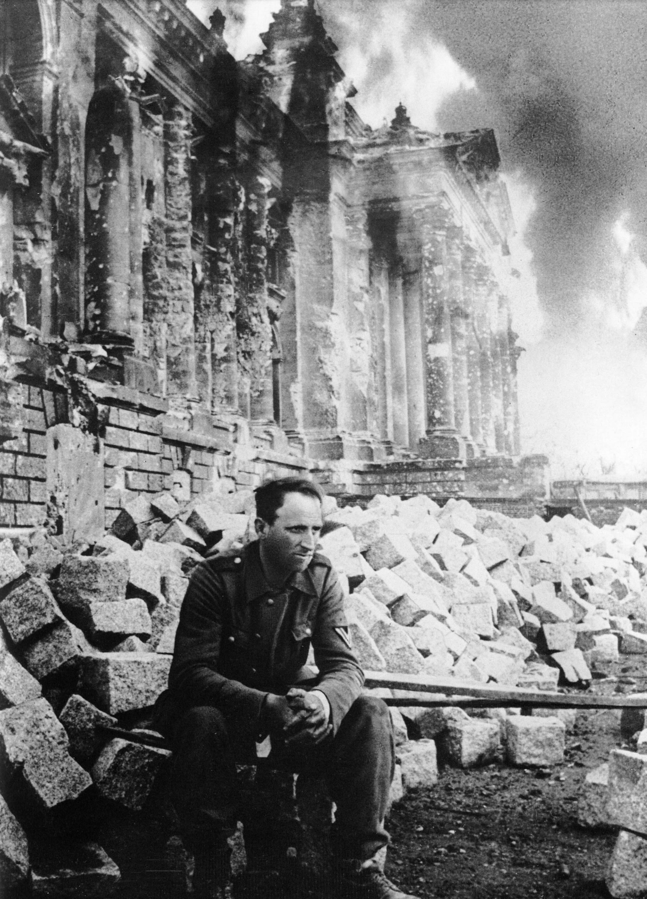 Пленный немецкий солдат на фоне горящего Рейхстага, Берлин, 1945 г. Знаменитая фотография, часто публиковавшаяся в книгах и на плакатах в СССР под названием "Энде" (нем. "Конец").