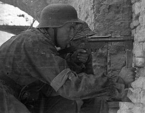 Варшавский повстанец Ежи Сикорский с пистолетом-пулеметом «Блыскавица» у стены дома на углу улиц Слепа и Пивна. 26 августа 1944.jpg