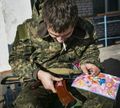 Солдат клеит на свой автомат Калашникова наклейки с персонажами детского мультика для девочек "Винкс".jpg