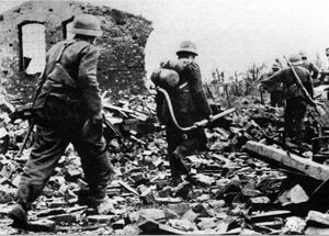 Немецкие солдаты идут по развалинам в городе Арнем в Нидерландах. В центре — огнеметчик. 1944 г..jpg