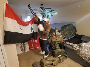 Человек в костюме фури и в советской униформе с АК и флагом Сирии, 2019 г..jpg