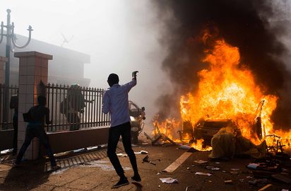 A car burns outside the parliament building in Burkina Faso as people protest against their longtime President Blaise Compaore who seeks another term in Ouagadougou, Burkina Faso, Thursday, Oct. 30, 2014.jpg
