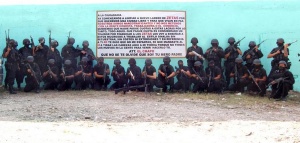 Gunmen associated with the Sinaloa Cartel pose in front of a sign threatening the Los Zetas Cartel..jpeg