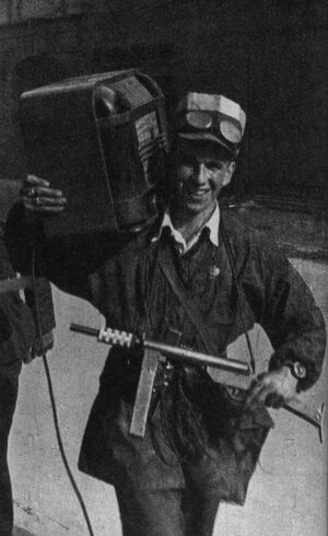 Варшавский повстанец, вооруженный 9-мм пистолетом-пулеметом «Блыскавица», несет радиоприемник. Варшава август 1944.jpg